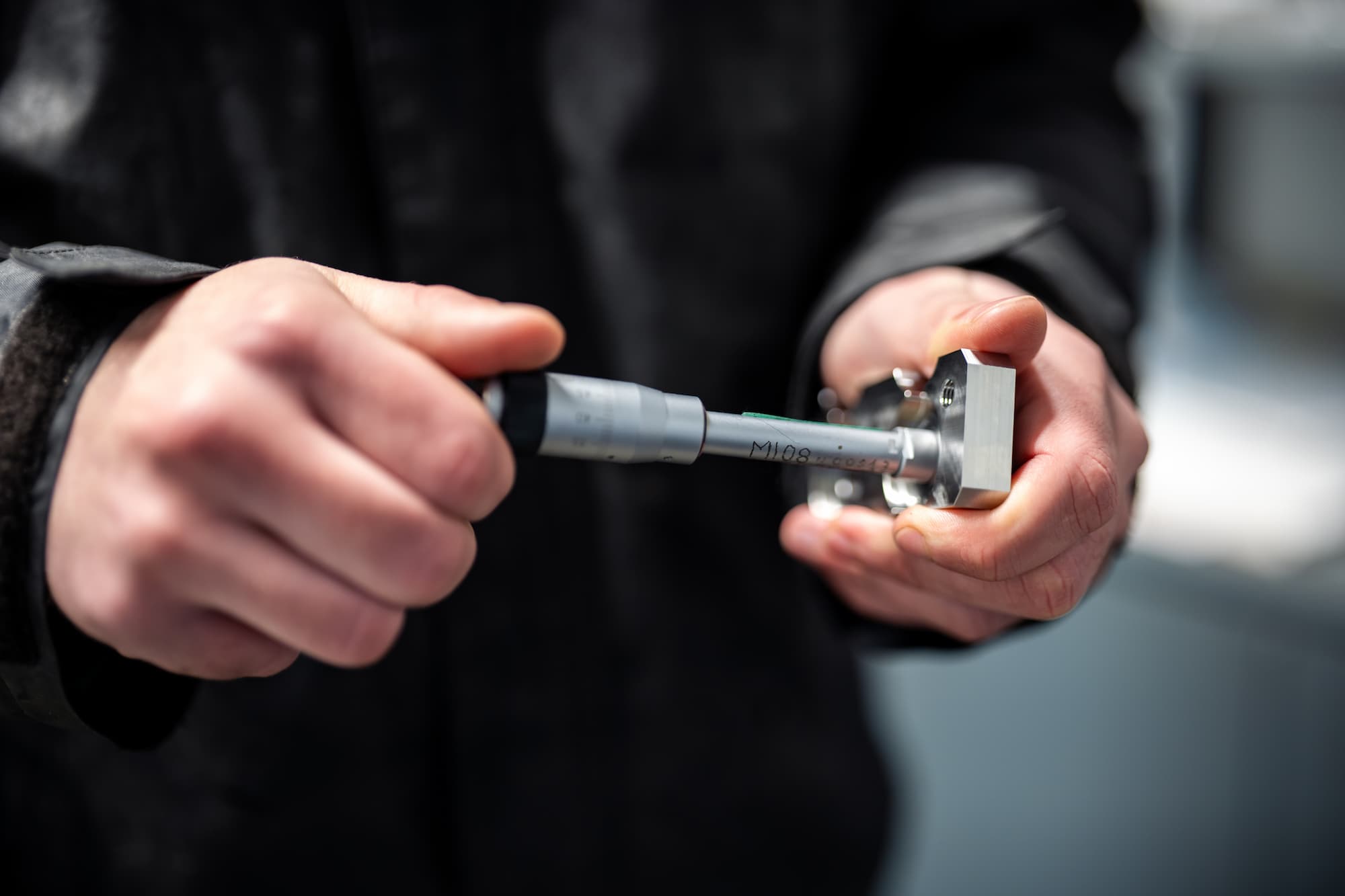 Technicien en atelier d’usinage industriel effectuant la mesure de précision d’une pièce mécanique avec un instrument de contrôle dimensionnel.