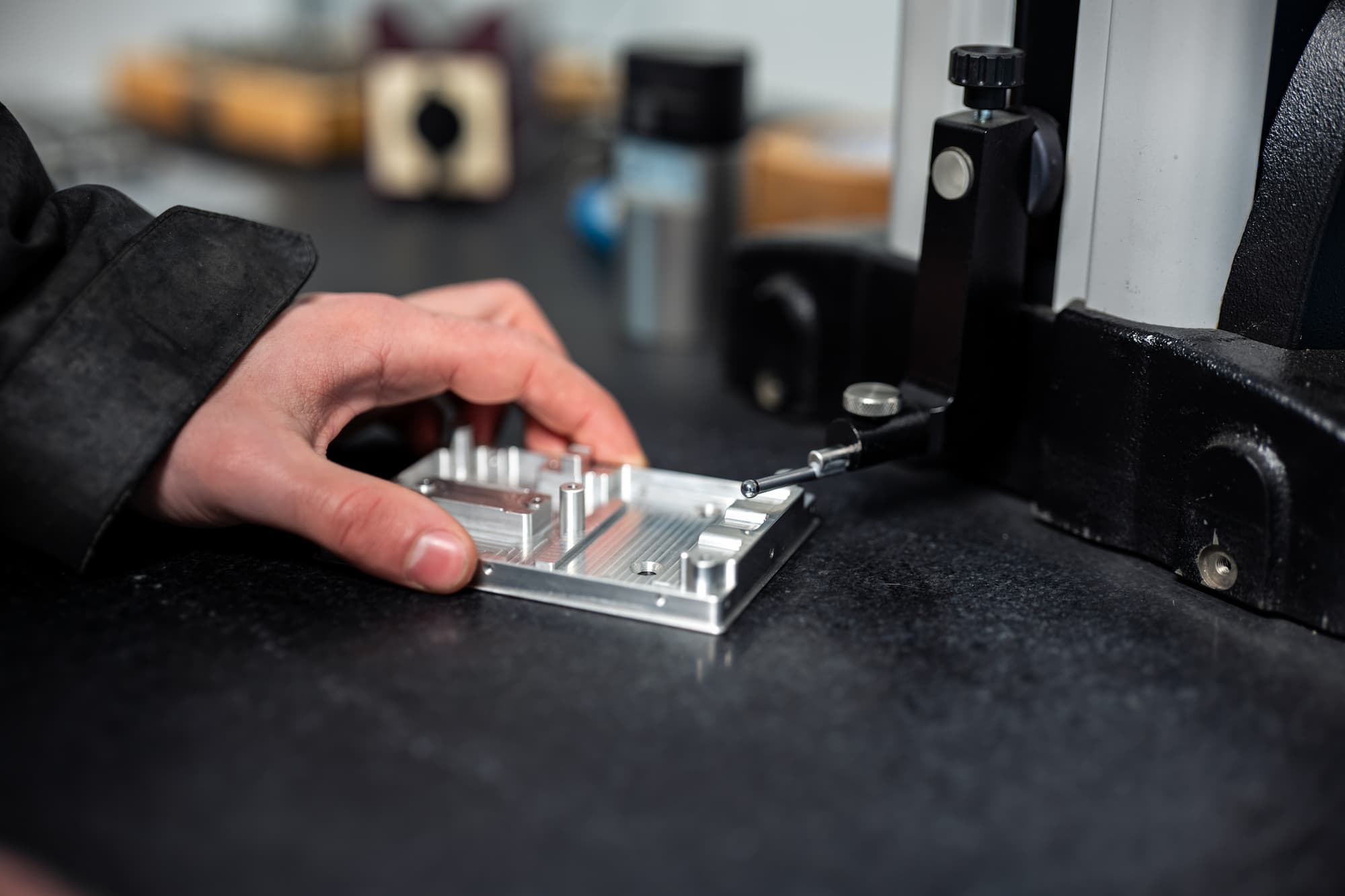 Mesure dimensionnelle d’une pièce mécanique en aluminium sur marbre de contrôle avec instrument de métrologie dans un atelier d’usinage industriel.