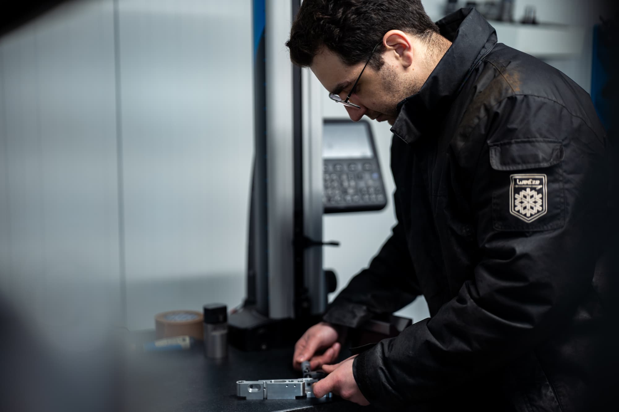 aurelien bel Technicien effectuant le contrôle dimensionnel d’une pièce mécanique en aluminium sur machine de mesure tridimensionnelle (CMM) dans un atelier d’usinage industriel.