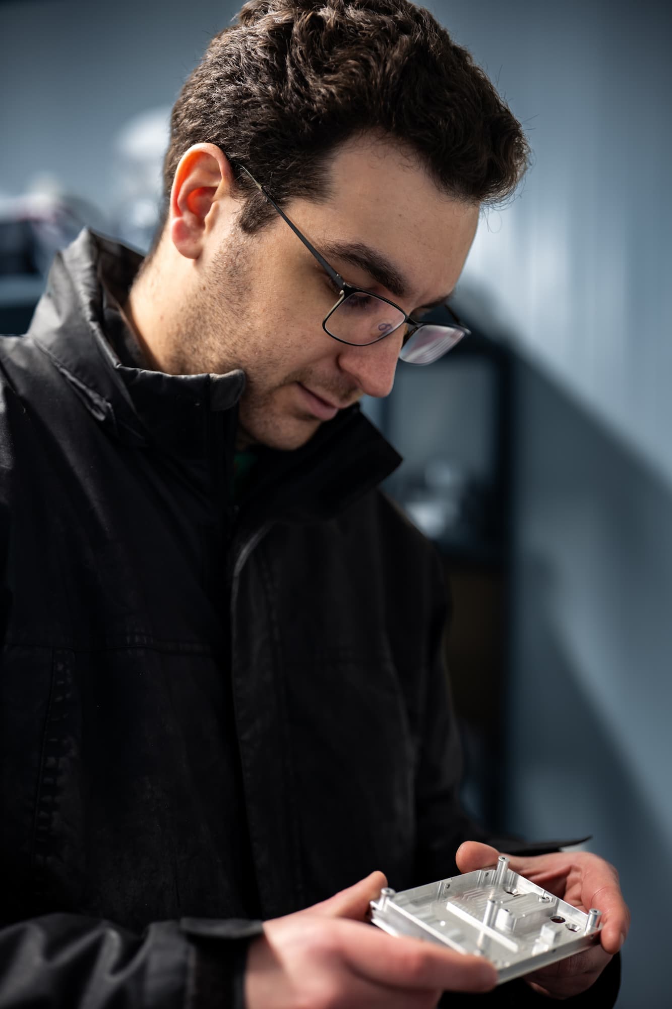 Technicien en atelier d’usinage inspectant une pièce mécanique de précision en aluminium dans le cadre d’un contrôle qualité industriel.