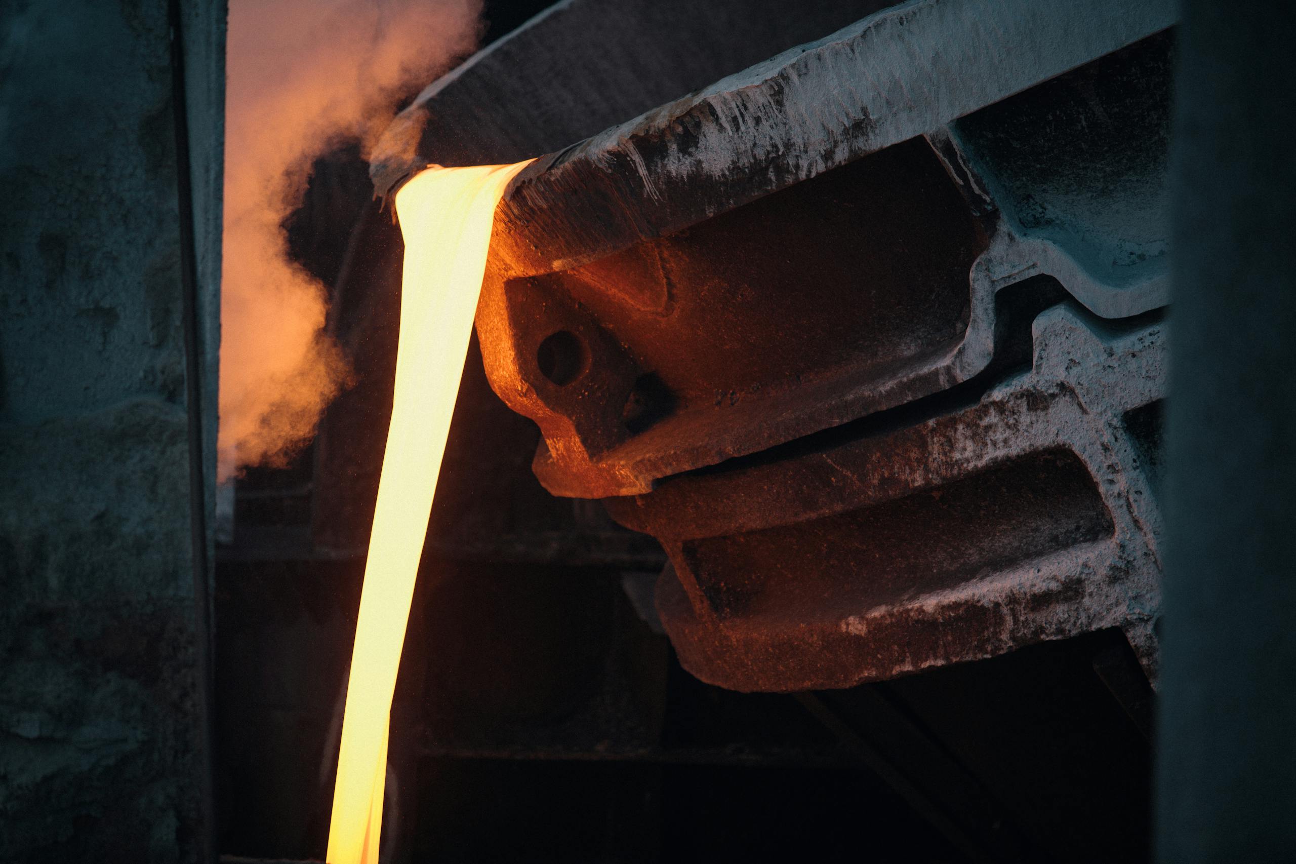 Molten metal pouring from ladle in industrial foundry, capturing the intense heat and energy.